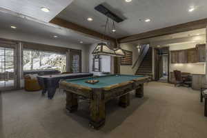 Playroom with beamed ceiling, billiards, built in desk, and light colored carpet