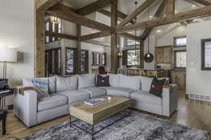 Living room featuring high vaulted ceiling, beamed ceiling, and light hardwood / wood-style flooring