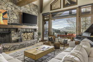 Living room with high vaulted ceiling, wood-type flooring, beamed ceiling, and a fireplace