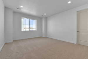 Carpeted spare room featuring a textured ceiling