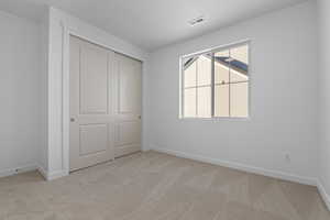 Unfurnished bedroom featuring light carpet and a closet