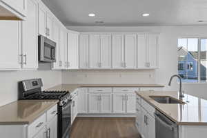 Kitchen with appliances with stainless steel finishes, sink, backsplash, dark hardwood / wood-style floors, and white cabinets