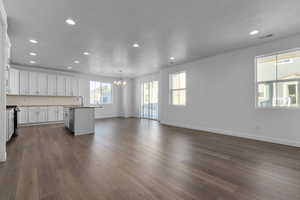 Kitchen featuring an island with sink, hanging light fixtures, sink, white cabinets, and dark hardwood / wood-style floors