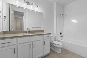 Full bathroom featuring toilet, vanity, tub / shower combination, and tile patterned flooring