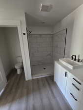 Full bathroom featuring wood finished floors, a shower stall, toilet, and vanity
