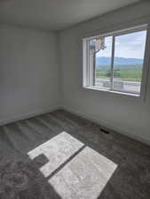 Carpeted empty room with baseboards and a mountain view