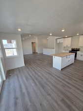 Kitchen with electric stove, open floor plan, dark wood-style flooring, butcher block counters, and white cabinetry