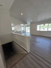 Kitchen featuring a peninsula, dark wood-style floors, recessed lighting, open floor plan, and white cabinets