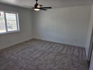 Spare room with carpet, a ceiling fan, and baseboards