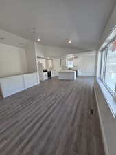 Unfurnished living room featuring vaulted ceiling, a sink, dark wood finished floors, recessed lighting, and baseboards