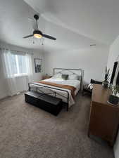 Bedroom with a textured ceiling, vaulted ceiling, dark colored carpet, and ceiling fan