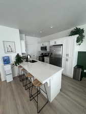 Kitchen with white cabinets, a kitchen bar, and stainless steel appliances