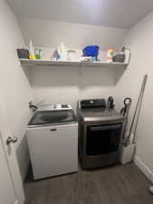 Clothes washing area with dark hardwood / wood-style floors and washer and clothes dryer