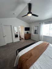 Bedroom with a textured ceiling, lofted ceiling, dark carpet, and ceiling fan