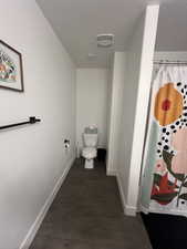 Bathroom with toilet, hardwood / wood-style floors, and curtained shower