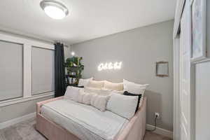 Bedroom featuring a textured ceiling and light colored carpet