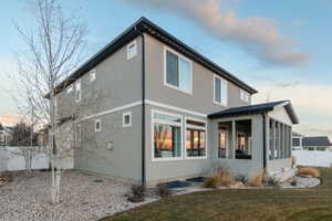 Property exterior at dusk with a yard and a sunroom