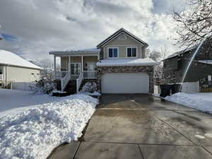 View of front facade with an attached garage, brick siding, fence, driveway, and stucco siding