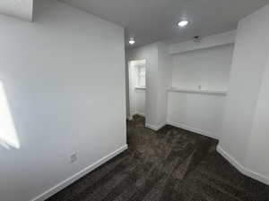 Interior space featuring dark colored carpet, a textured ceiling, baseboards, and recessed lighting