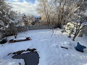 Yard layered in snow featuring a fenced backyard