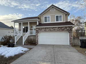 View of front of house featuring a porch, an attached garage, brick siding, driveway, and stucco siding