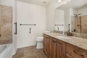 Full bathroom with tiled shower / bath combo, vanity, and toilet