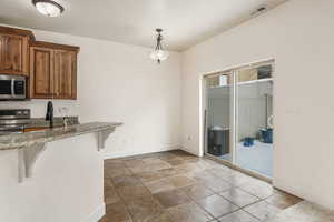 Kitchen with appliances with stainless steel finishes, pendant lighting, and a breakfast bar