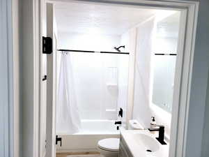 Full bathroom with toilet,  Smart mirror vanity, a textured ceiling, and shower / bath combination with curtain