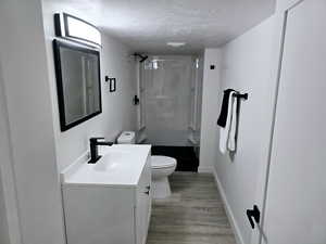 Bathroom featuring wood-type flooring, vanity, a textured ceiling, and walk in shower