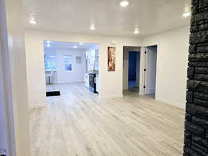 Unfurnished living room with a textured ceiling, recessed lighting, wood finished floors, and baseboards