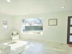 Living room with light wood-type flooring and a textured ceiling large bay window