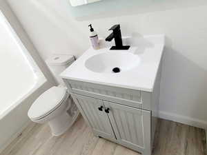 Full bathroom with hardwood / wood-style flooring, shower / bathtub combination, vanity, and toilet