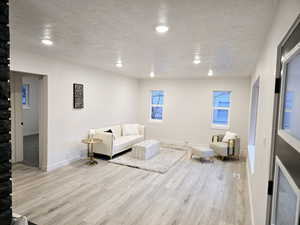 Living room with light wood-type flooring and a textured ceiling large bay window
