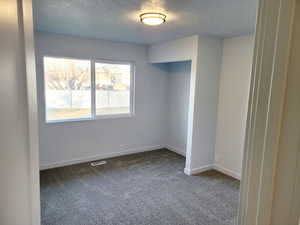 2nd bedroom with a textured ceiling and carpet flooring