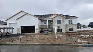 View of front of house featuring stone siding, driveway, and an attached garage