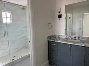 Bathroom featuring baseboards, vanity, and a stall shower