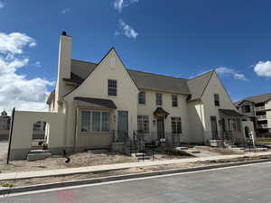 View of front of house with roof with shingles, a chimney, and stucco siding