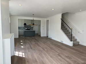 Unfurnished living room featuring stairway, dark wood finished floors, and visible vents