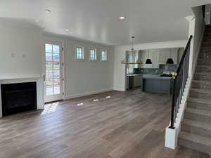 Unfurnished living room featuring light wood-type flooring, baseboards, stairs, a fireplace, and ornamental molding