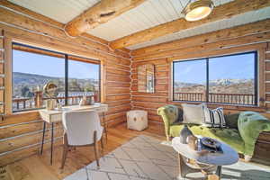 Interior space with a mountain view, log walls, hardwood / wood-style floors, and beamed ceiling