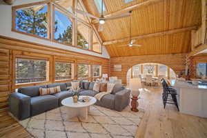 Living room featuring a skylight, high vaulted ceiling, light hardwood / wood-style flooring, beamed ceiling, and ceiling fan