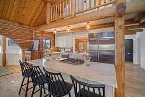 Kitchen featuring beamed ceiling, stainless steel appliances, a breakfast bar, and white cabinets