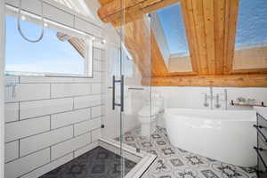 Full bathroom with tile patterned floors, toilet, shower with separate bathtub, a skylight, and vanity