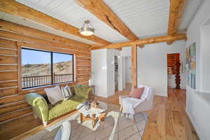 Living room with beamed ceiling, wood ceiling, and light hardwood / wood-style floors