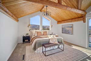 Carpeted bedroom with lofted ceiling with beams, access to outside, wooden ceiling, a mountain view, and a notable chandelier