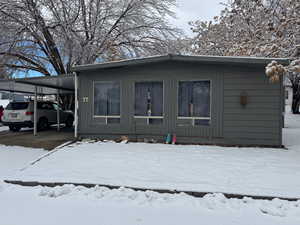 View of snow covered exterior with a carport