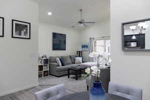 Living room featuring hardwood / wood-style flooring, vaulted ceiling, and ceiling fan