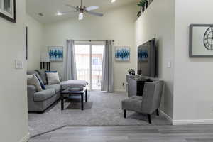 Living room with ceiling fan, high vaulted ceiling, and wood-type flooring