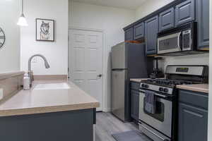 Kitchen featuring decorative light fixtures, light hardwood / wood-style floors, stainless steel appliances, and sink