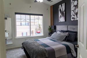 Carpeted bedroom featuring ceiling fan and vaulted ceiling